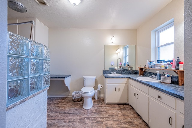 bathroom with vanity, wood-type flooring, a textured ceiling, toilet, and walk in shower