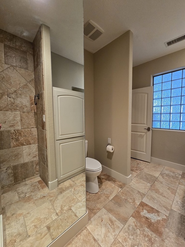 6101 Fm 715, Midland, TX 79706 - bathroom with stone tile flooring, toilet, a tile shower, and baseboards