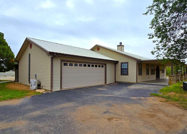6101 Fm 715, Midland, TX 79706 - view of front facade with a chimney, driveway, metal roof, an attached garage, and ac unit