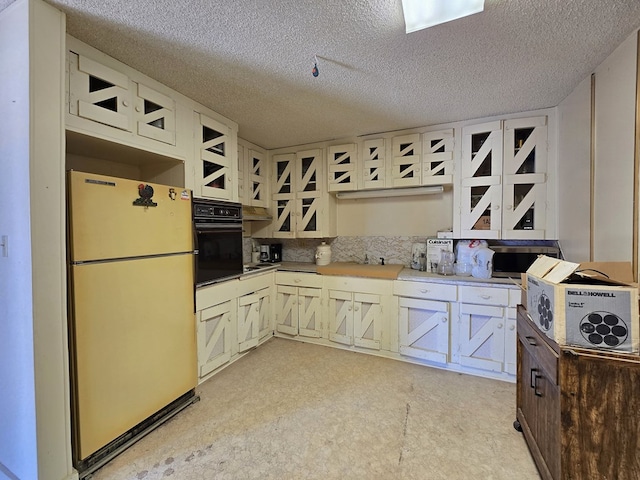 6101 Fm 715, Midland, TX 79706 - kitchen featuring freestanding refrigerator, black oven, and a textured ceiling