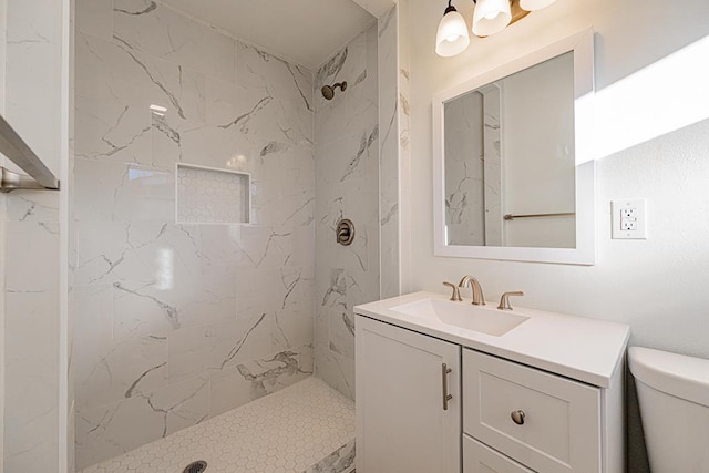 bathroom featuring tiled shower, vanity, and toilet