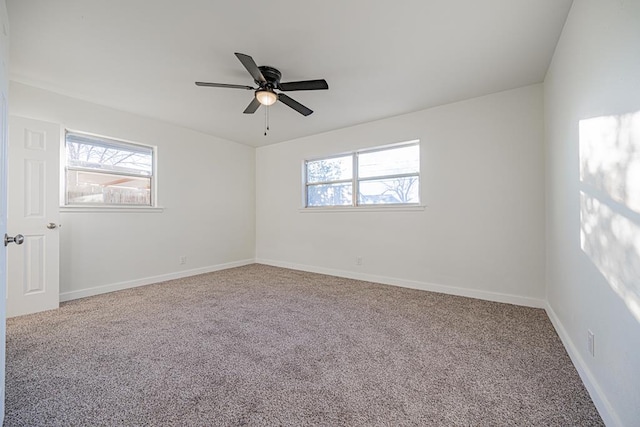 empty room featuring a wealth of natural light, carpet floors, and ceiling fan