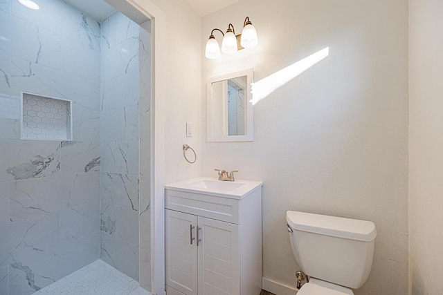 bathroom featuring vanity, tiled shower, and toilet