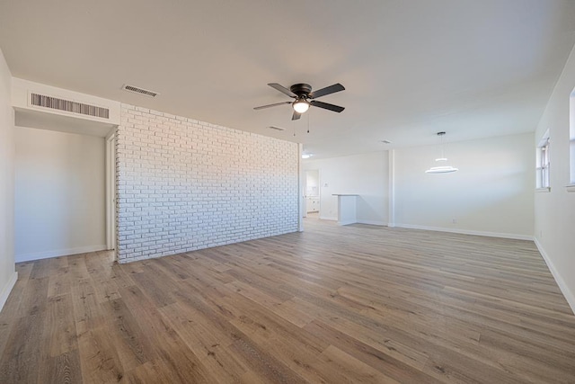 unfurnished room with ceiling fan, brick wall, and hardwood / wood-style floors