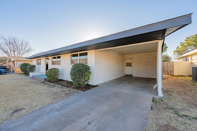 ranch-style home featuring central AC unit and a carport