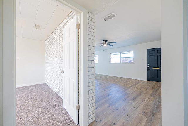 corridor featuring light wood-type flooring and brick wall