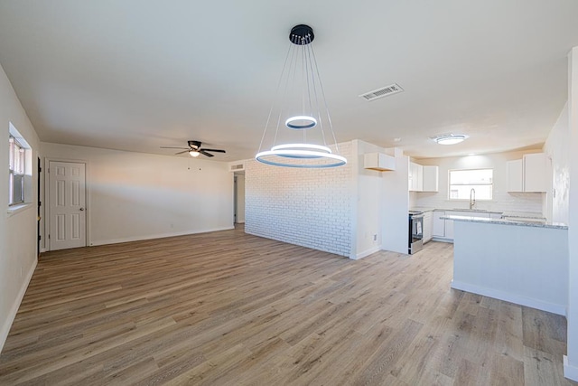 kitchen featuring white cabinetry, stainless steel range with electric stovetop, ceiling fan, and light wood-type flooring