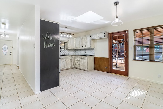 kitchen with tasteful backsplash, pendant lighting, a skylight, and light tile patterned flooring