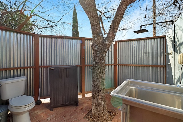 exterior space with toilet, brick floor, and a sink