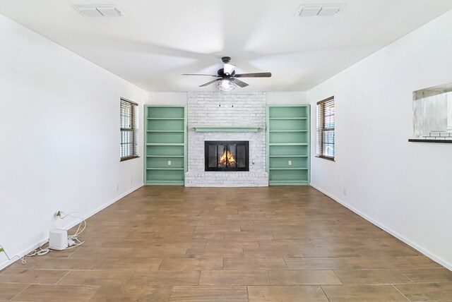 unfurnished living room with baseboards, a fireplace, visible vents, and ceiling fan