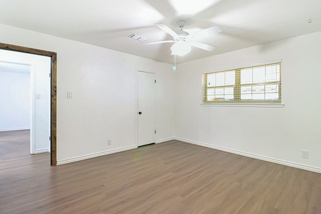 spare room featuring ceiling fan, visible vents, baseboards, and wood finished floors