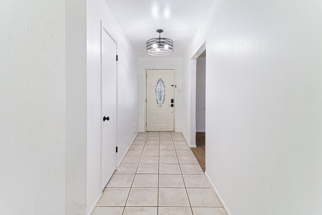 entryway featuring light tile patterned flooring, baseboards, and a chandelier