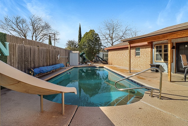 view of swimming pool featuring a fenced in pool, a fenced backyard, an outdoor structure, a storage unit, and a patio area