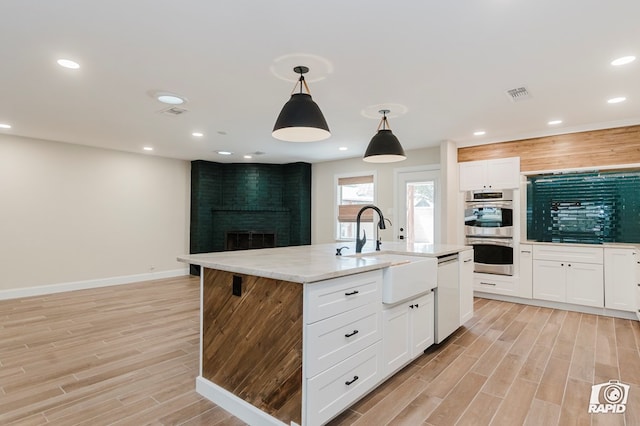 kitchen featuring visible vents, dishwasher, a sink, double oven, and light wood-style floors