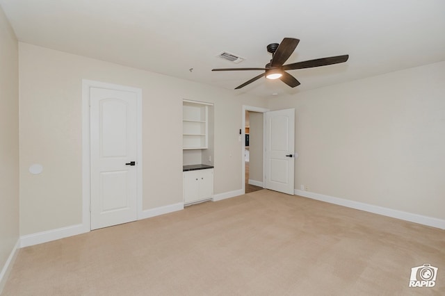 unfurnished bedroom featuring baseboards, visible vents, light carpet, and ceiling fan