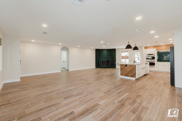 kitchen featuring arched walkways, freestanding refrigerator, recessed lighting, open floor plan, and visible vents