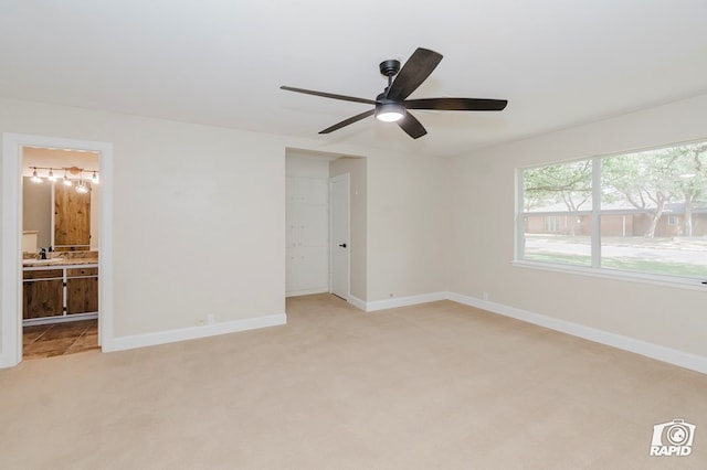 unfurnished bedroom with light colored carpet, a sink, baseboards, and ensuite bathroom