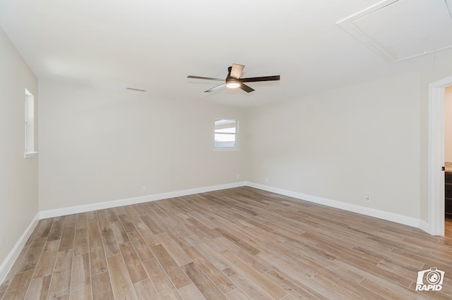 spare room with a ceiling fan, visible vents, light wood finished floors, and attic access