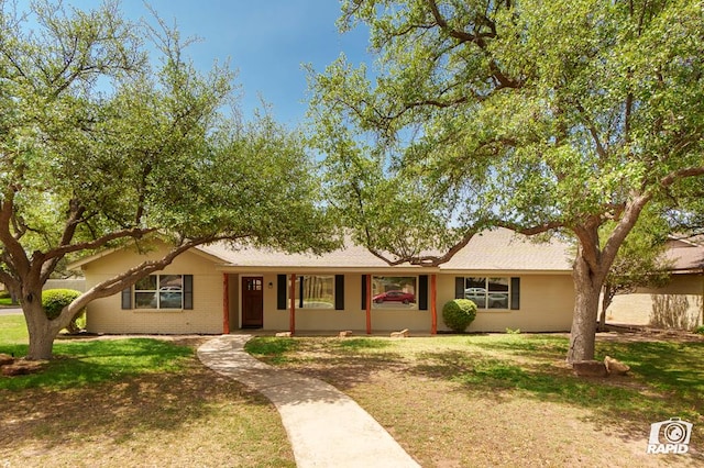 single story home featuring a porch, brick siding, and a front yard