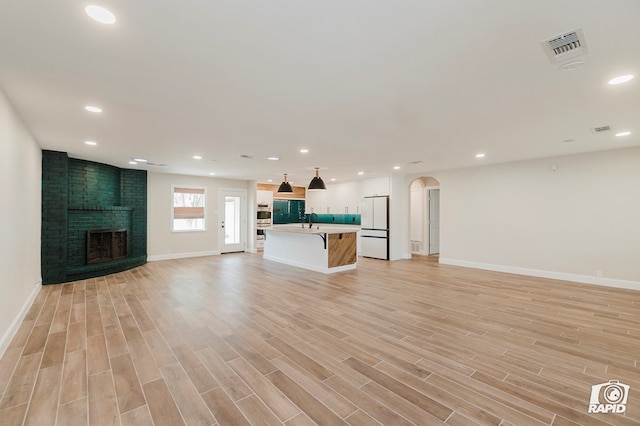 unfurnished living room featuring baseboards, recessed lighting, light wood finished floors, and visible vents