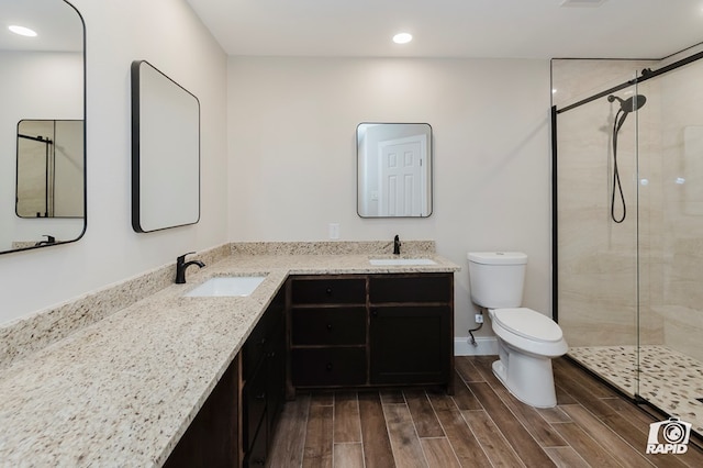 bathroom featuring recessed lighting, toilet, a sink, and a stall shower