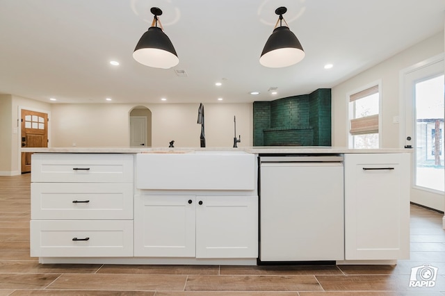 kitchen with white cabinetry, wood finish floors, a sink, and dishwasher