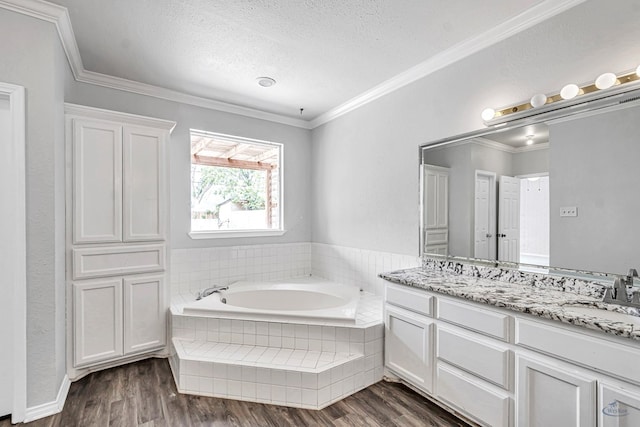 2008 Bedford Dr, Midland, TX 79701 - bathroom featuring a textured ceiling, double vanity, a bath, wood finished floors, and crown molding