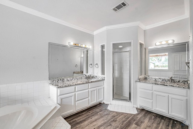 2008 Bedford Dr, Midland, TX 79701 - bathroom with ornamental molding, a shower stall, a garden tub, wood finished floors, and two vanities