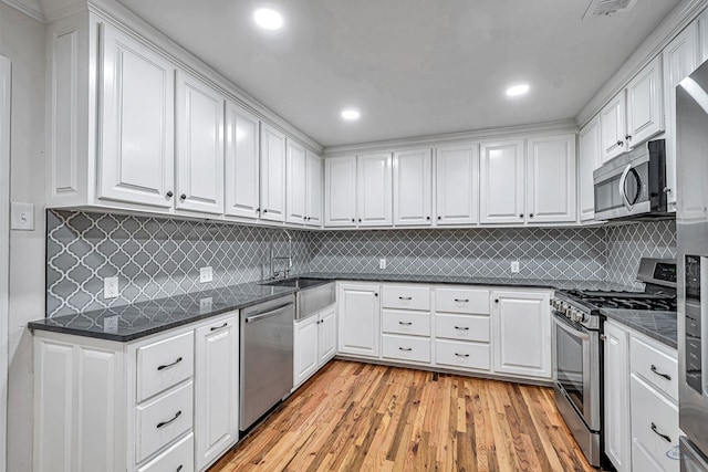 2008 Bedford Dr, Midland, TX 79701 - kitchen with stainless steel appliances, white cabinets, light wood finished floors, tasteful backsplash, and recessed lighting
