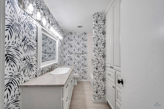2008 Bedford Dr, Midland, TX 79701 - bathroom featuring wallpapered walls, toilet, and vanity
