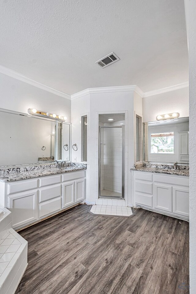 2008 Bedford Dr, Midland, TX 79701 - full bathroom featuring ornamental molding, a stall shower, wood finished floors, a textured ceiling, and two vanities