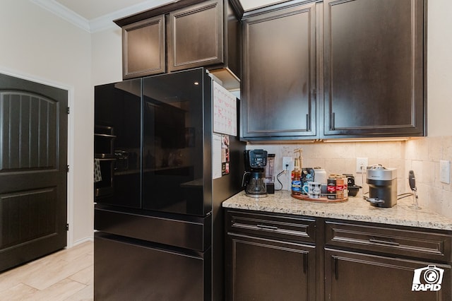 kitchen with dark brown cabinetry, decorative backsplash, crown molding, and freestanding refrigerator