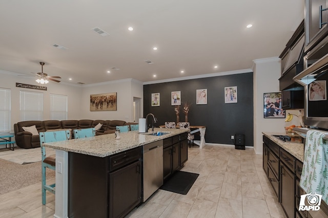 kitchen with visible vents, dishwasher, an island with sink, light stone countertops, and a kitchen bar