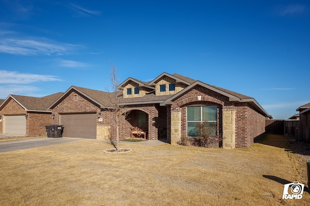 view of front of house with brick siding, concrete driveway, an attached garage, fence, and a front lawn