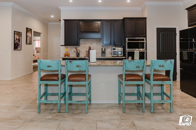 kitchen with a breakfast bar, ornamental molding, backsplash, and stainless steel double oven