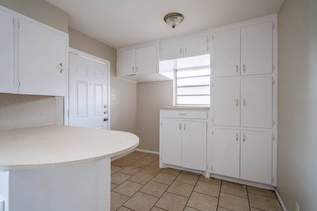 kitchen with white cabinets, light countertops, baseboards, and light tile patterned floors