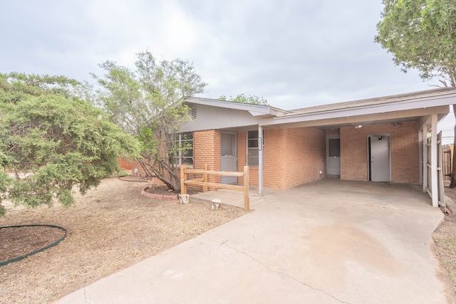 view of front of house with brick siding, concrete driveway, and an attached carport