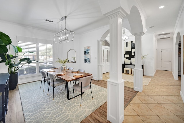 dining space with decorative columns, crown molding, light hardwood / wood-style floors, and a notable chandelier