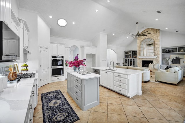 kitchen featuring white cabinets, appliances with stainless steel finishes, a center island with sink, and built in features