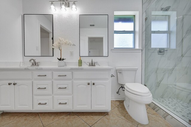 bathroom featuring tile patterned flooring, vanity, toilet, and a tile shower