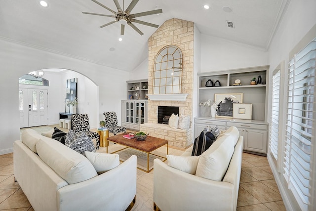 tiled living room with ceiling fan, built in features, a fireplace, and high vaulted ceiling