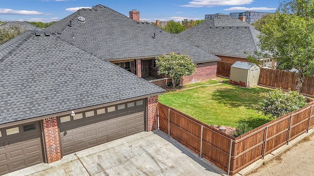 exterior space featuring a garage, a storage unit, and a lawn