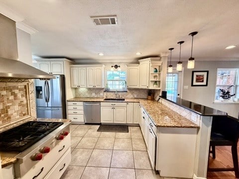 3302 Cord Dr, Midland, TX 79705 - kitchen with appliances with stainless steel finishes, wall chimney exhaust hood, a peninsula, a kitchen breakfast bar, and open shelves