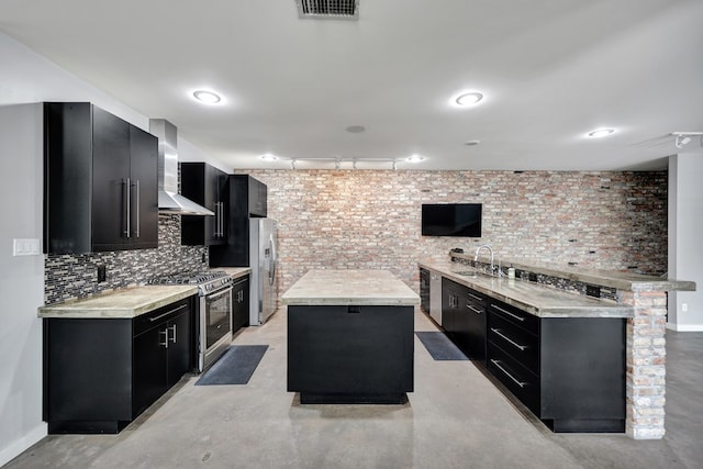 kitchen featuring dark cabinets, track lighting, a kitchen island, and appliances with stainless steel finishes