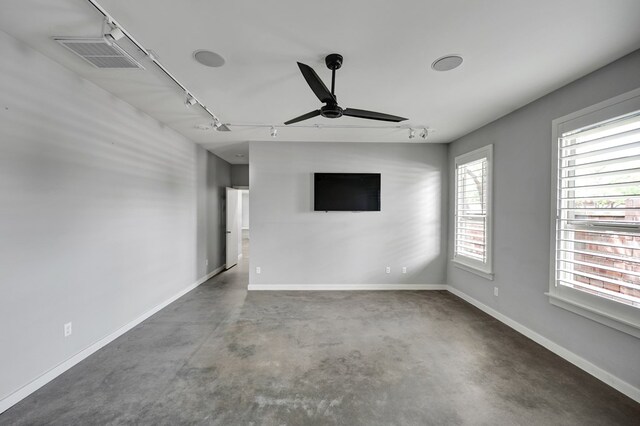empty room featuring concrete floors, ceiling fan, rail lighting, baseboards, and visible vents