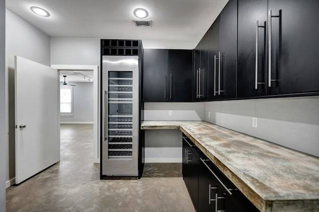 kitchen featuring visible vents, finished concrete floors, dark cabinetry, and wine cooler