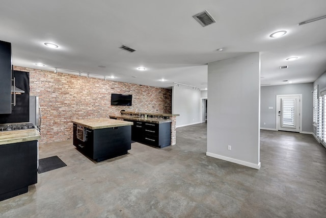 kitchen featuring concrete floors, a kitchen island, dark cabinetry, and visible vents