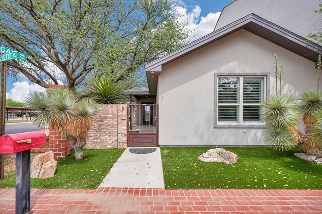 view of front of house featuring a gate, a front yard, and stucco siding