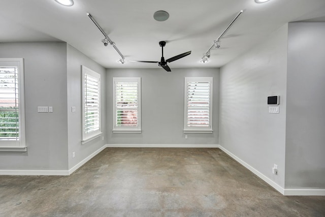 unfurnished dining area with track lighting, concrete floors, baseboards, and a ceiling fan