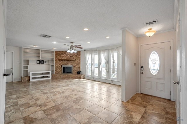 foyer entrance with visible vents, a brick fireplace, and a healthy amount of sunlight